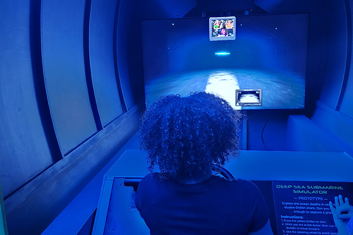 A girl with curly hair looks at a screen in a blue room