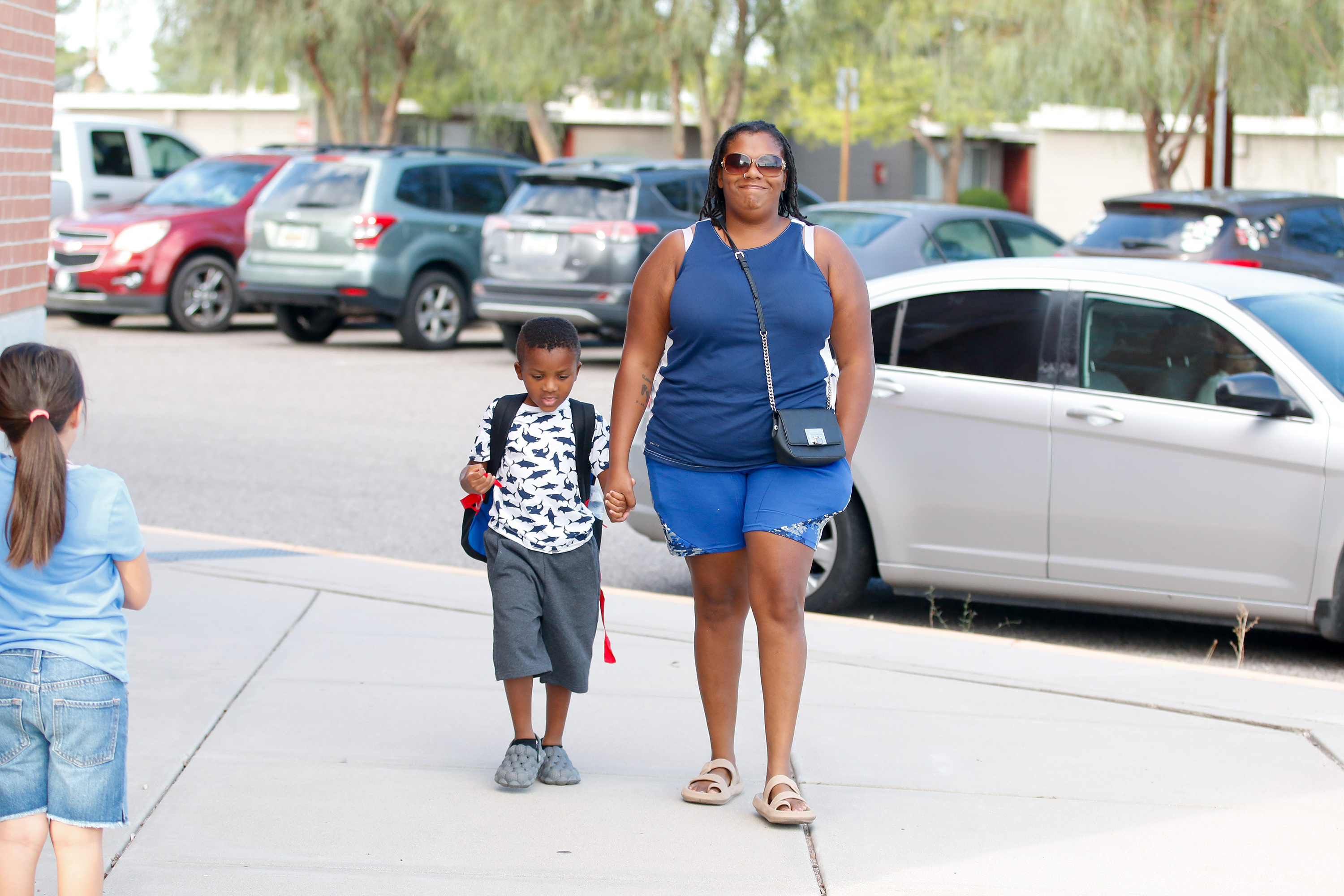 A mom walks holding her son's hand on the second day of school