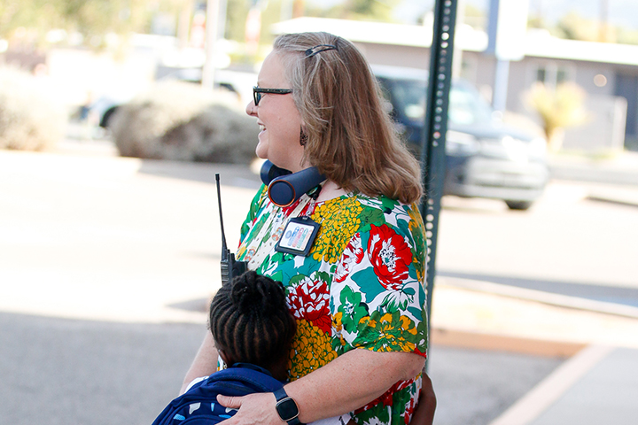A woman in a floral dress hugs a little girl