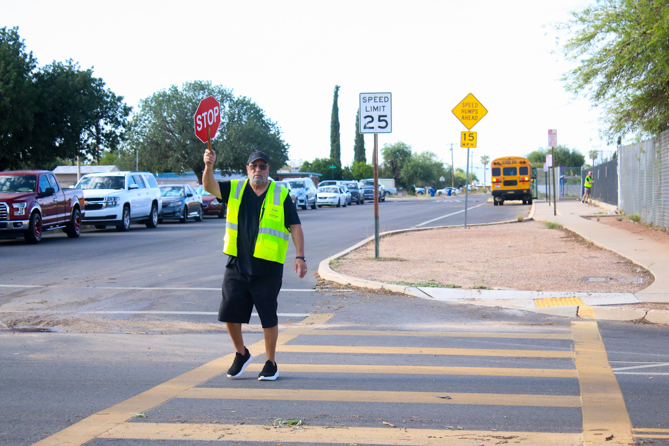 The crossing guard holds up his stop sign as he crosses the street