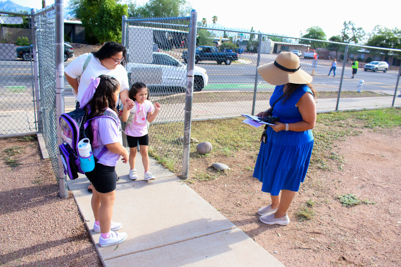 A woman welcomes a mom and her two little girls to campus