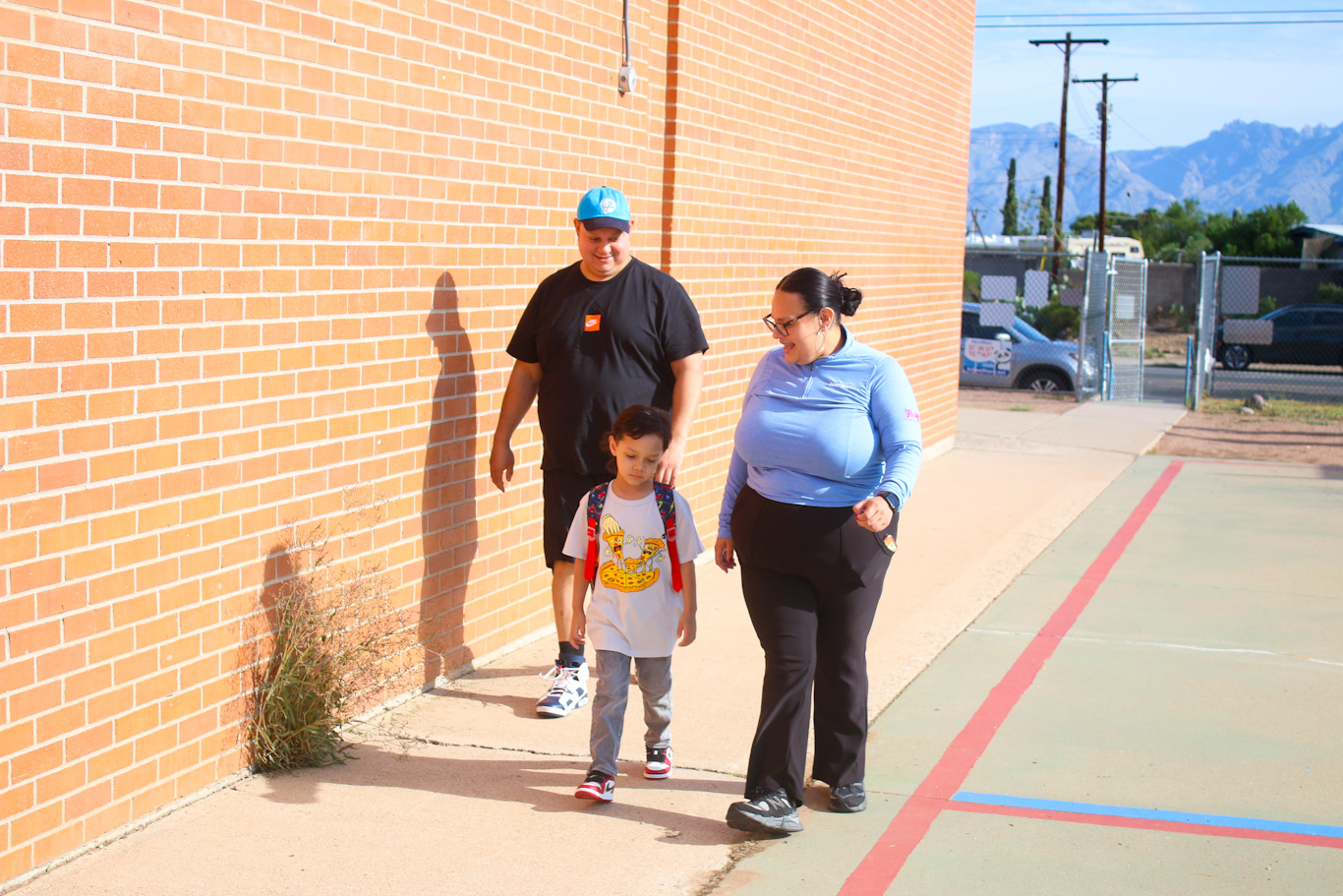 Parents walk with their little boy into school