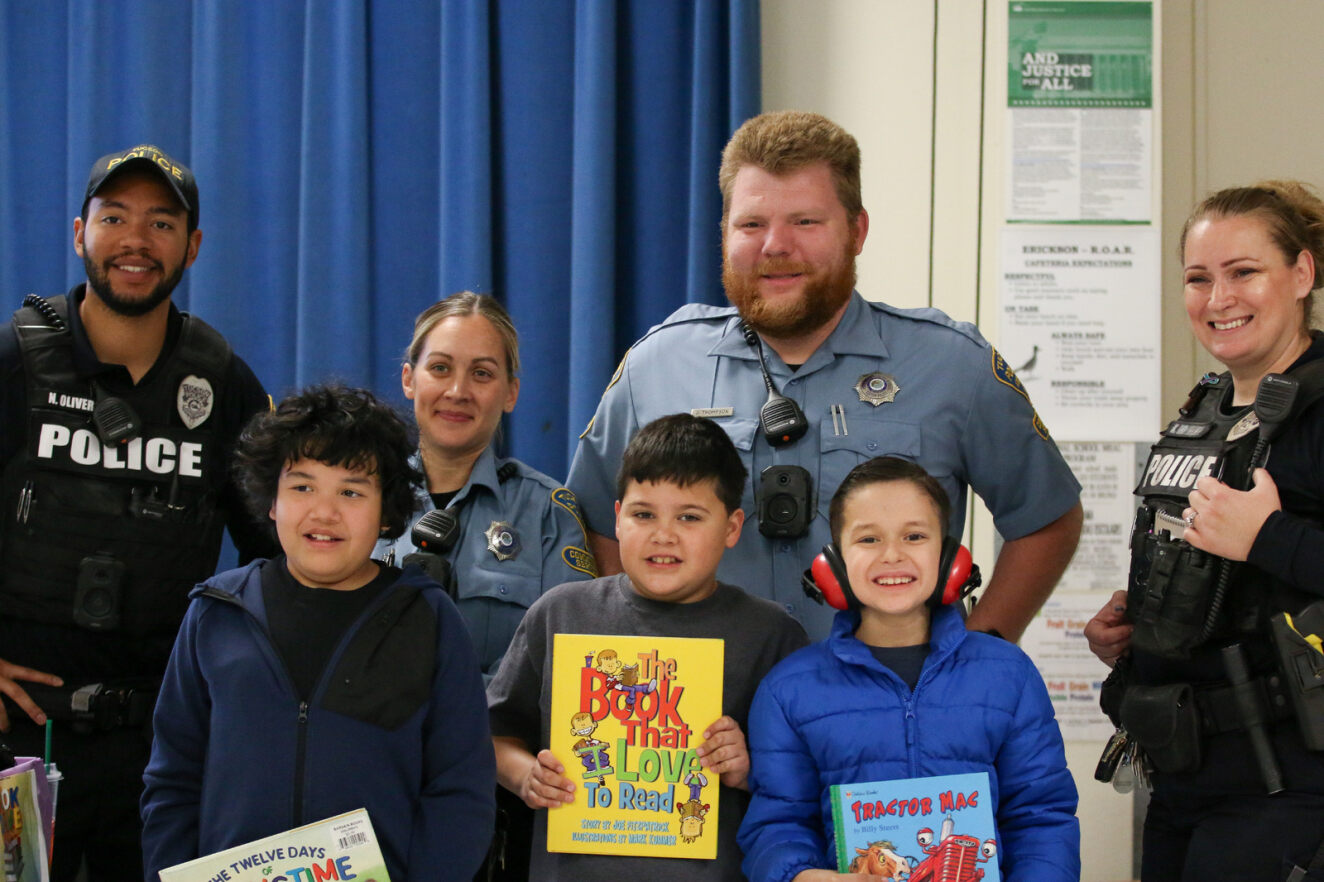 Tucson Police officers pose with a few students they donated books to.