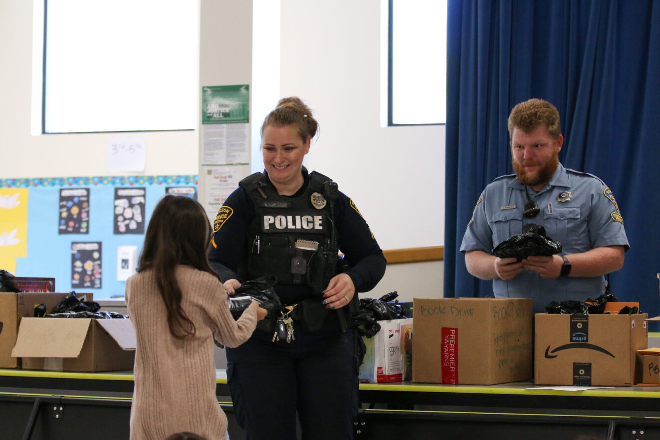 A TPD officer hands a young girl a book.