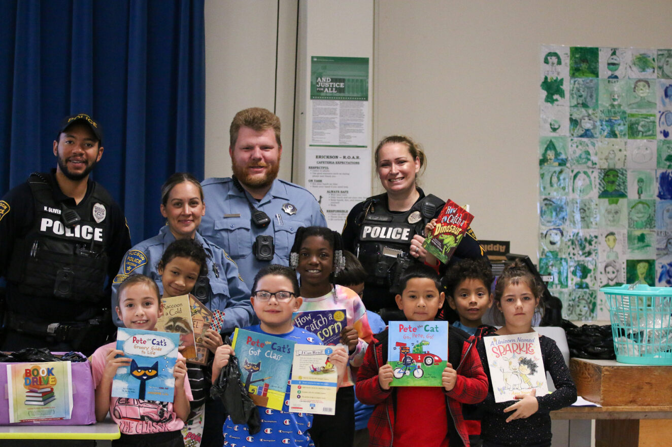 Tucson Police officers smile with a group of students and their new books.